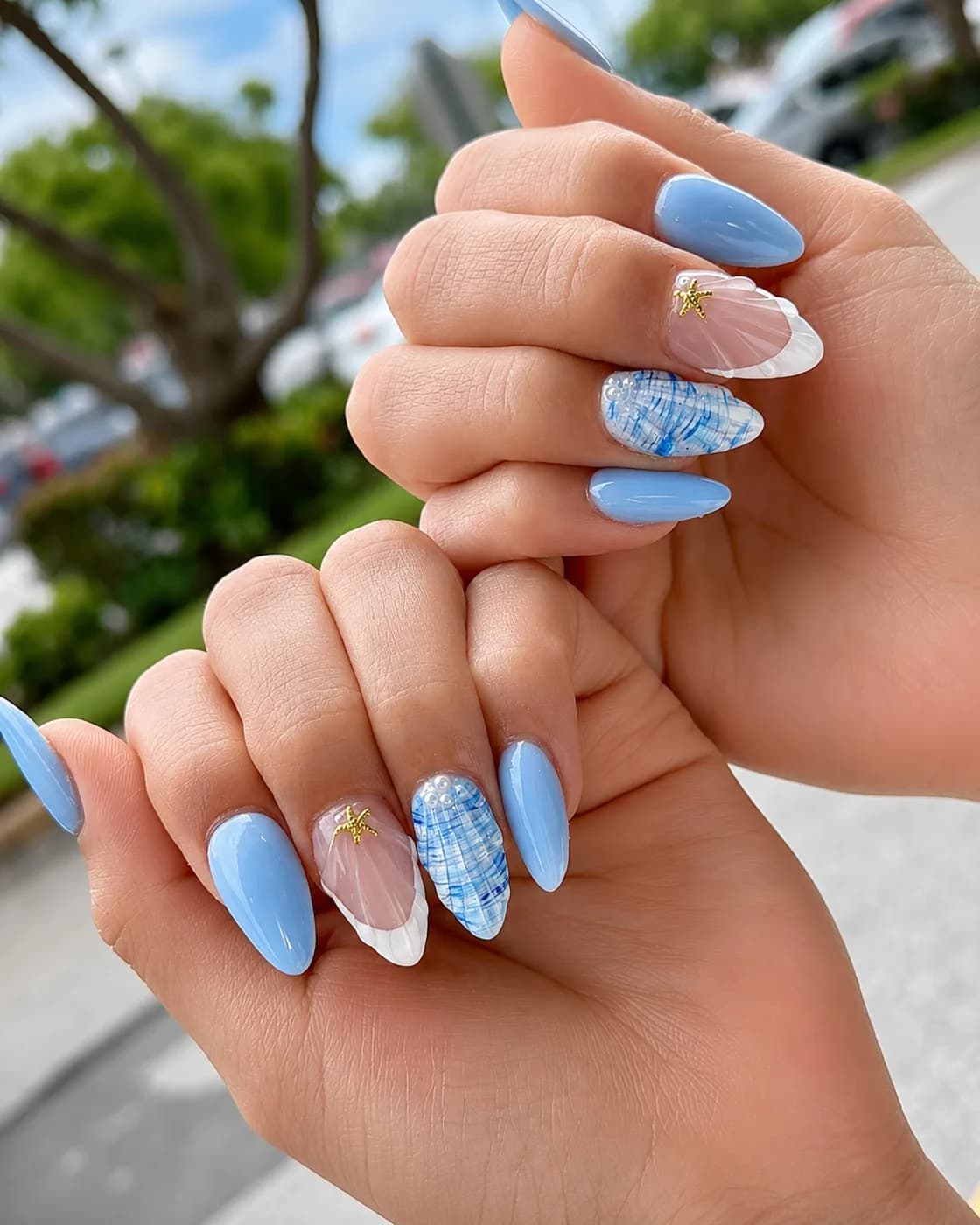 Almond nails in powder blue with a white marble-effect accent nail